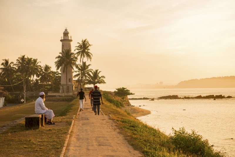 Galle Fort Sunrise 2 A few people walking at sunrise on the ramparts of Galle Fort next to the ocean