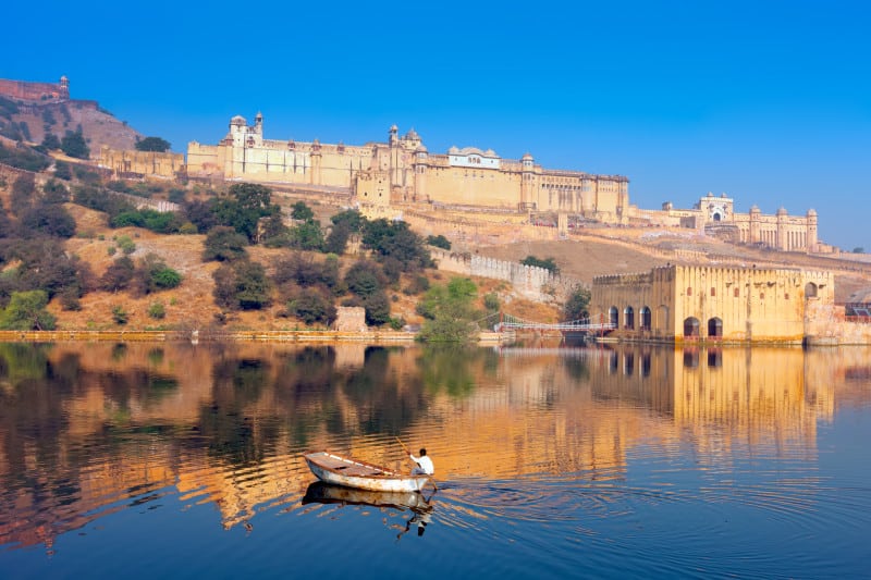 Maota Lake and Amber Fort in Jaipur View of the Amber Fort with a lake and fisherman in the foreground and blue sky in the background