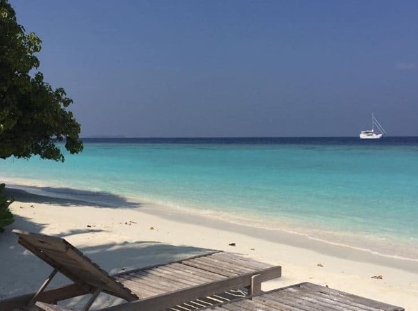 maldives beach lounge chais lounge chairs on the beach in the Maldives overlooking the turquoise blue waters