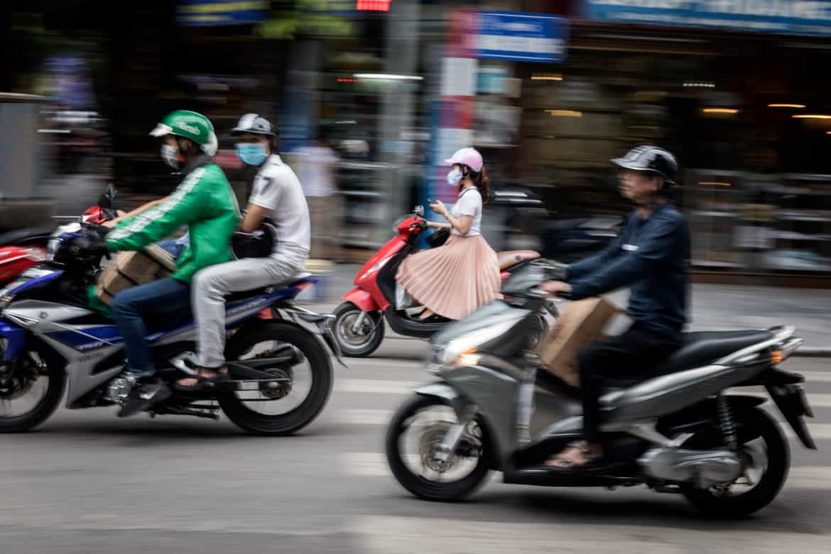 Locals commuting on motorbikes in Ho Chi Minh City with shopfront blurred in the background