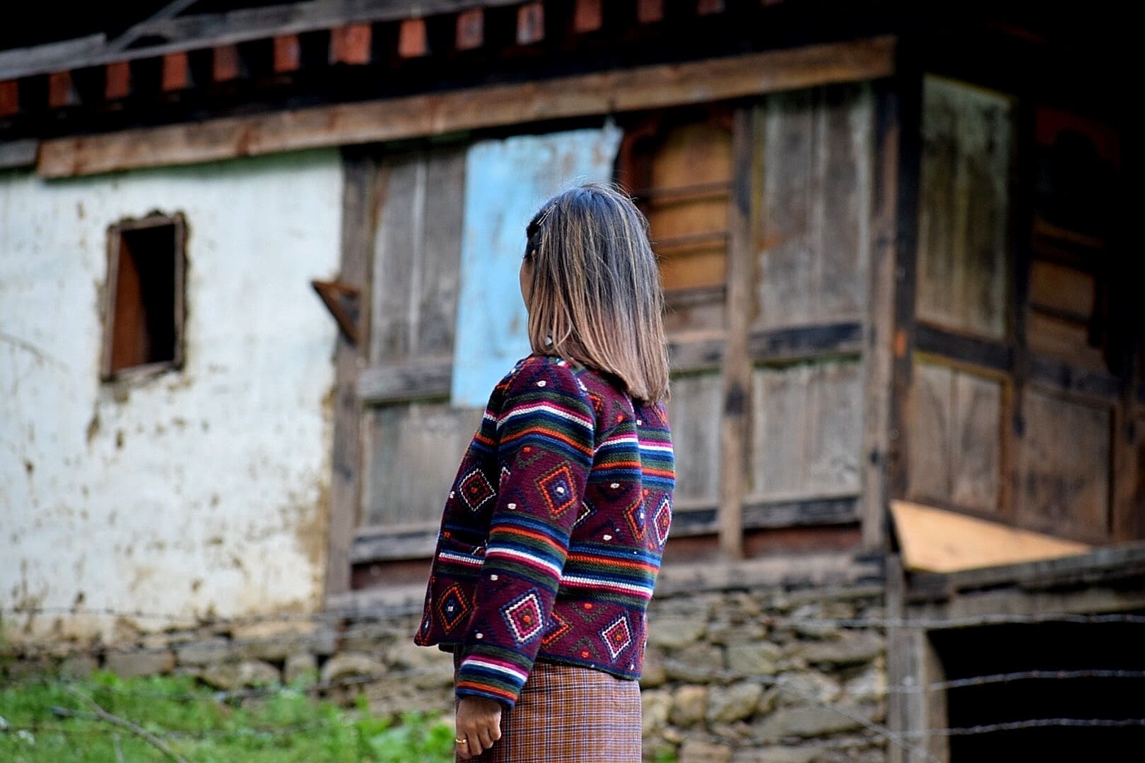 She Bhutan 3 Woman turned away from the camera wearing a traditional Bhutanese weaving jacket
