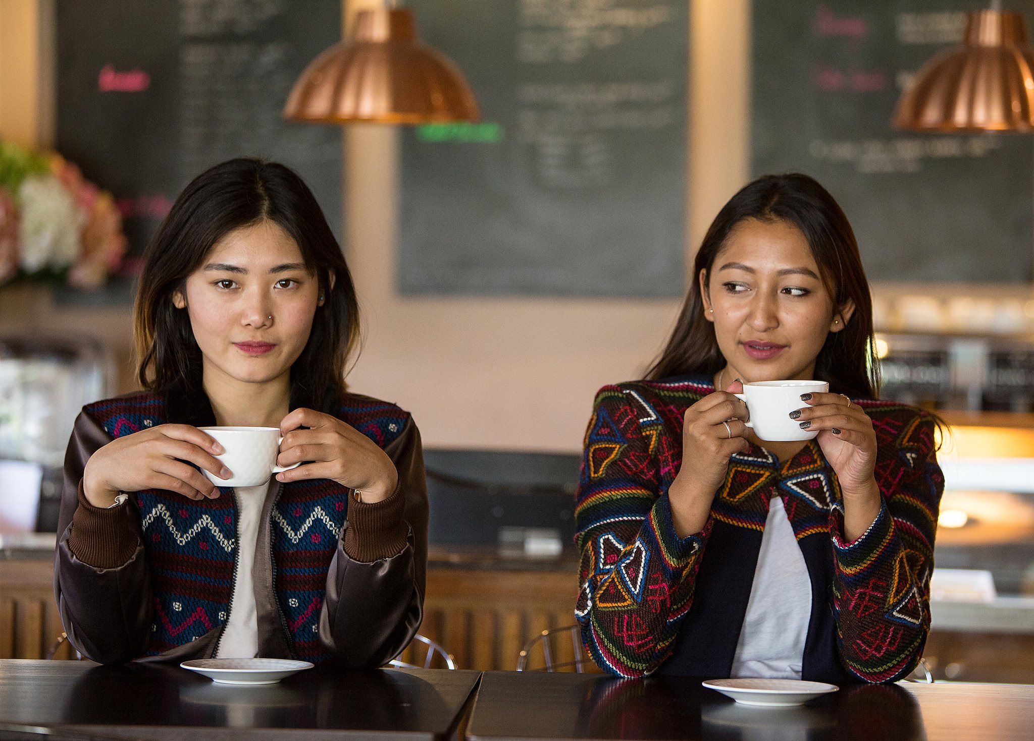 She Bhutan Two young Bhutanese woman sat next each other in a cafe, drinking a hot drink