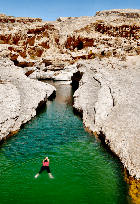 Swimming in Oman A person swimming in Wadi Bani Khalid - a narrow waterway of green water surrounded by a canyon