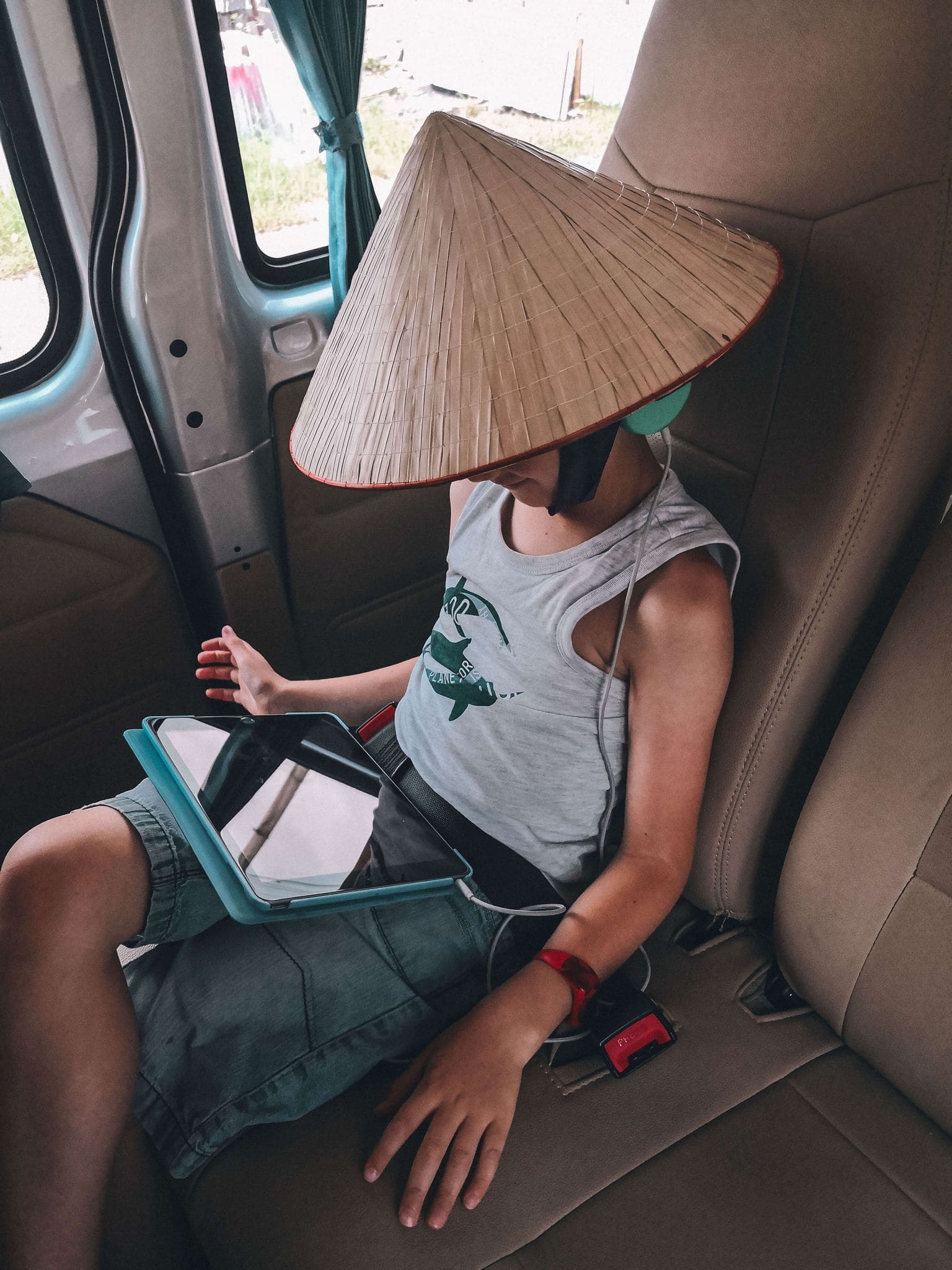 Kids Travel Technology Child wearing traditional vietnamese conical hat whilst on his tablet