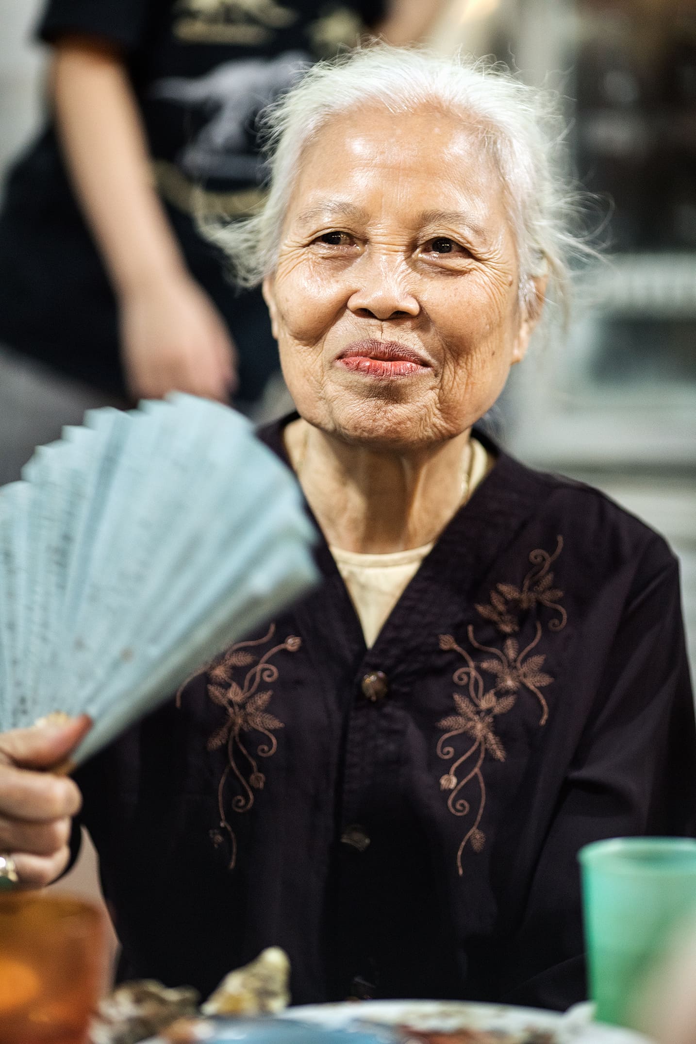 nominate a hero Old local woman eating Street food in Hanoi in the evening