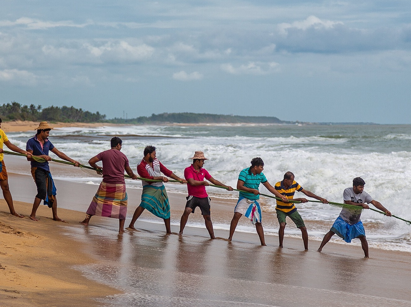 Men hauling in fish on Sri Lankan beach at Ravana Garden hotel Men hauling in fish on Sri Lankan beach at Ravana Garden hotel