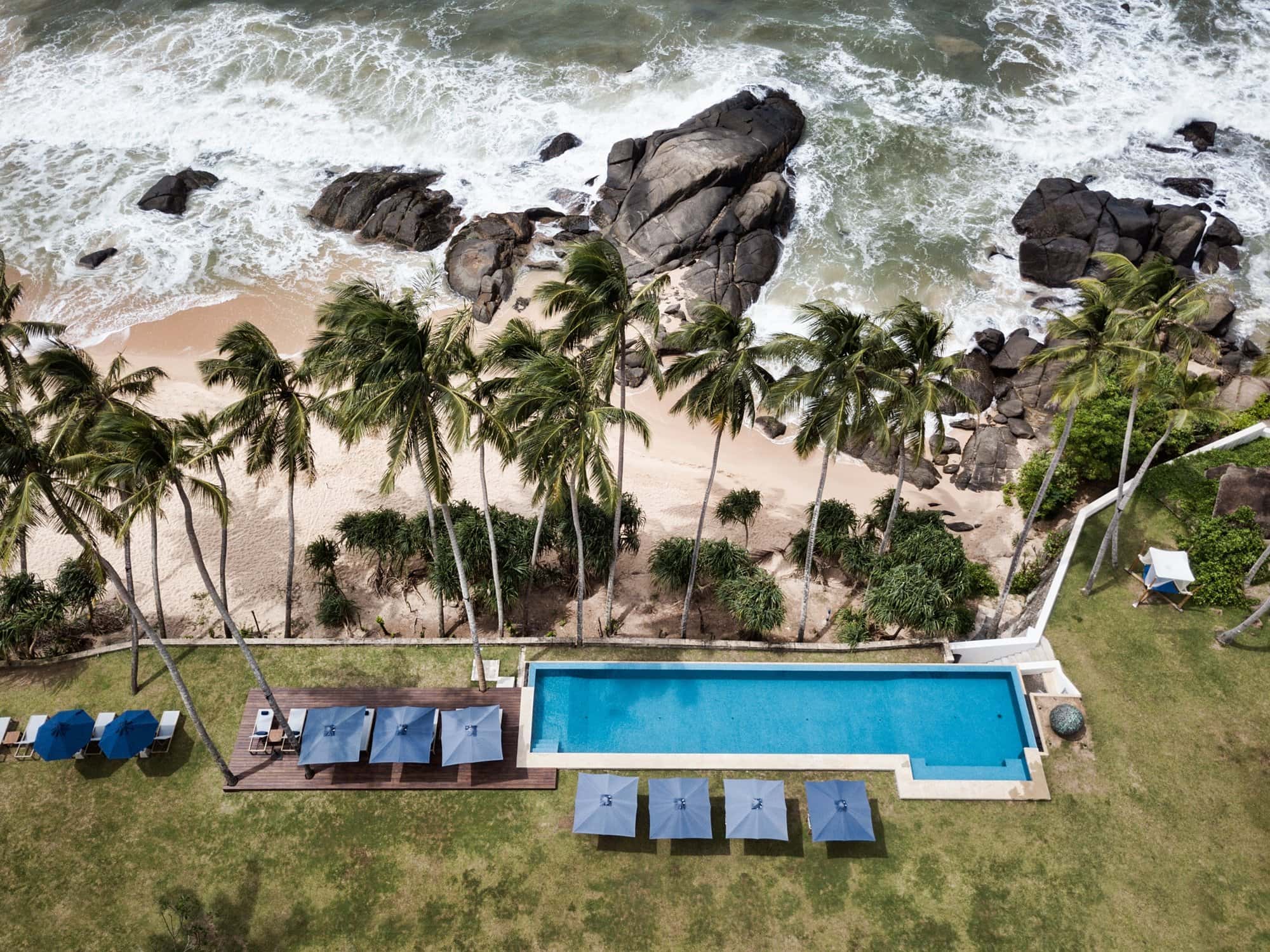 Aerial Shot of Kumu Beach near Bentota Aerial shot of Kumu Beach swimming pool with palm trees and rocky beach