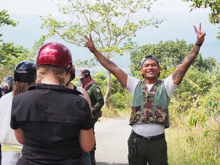 Guide in Cambodia Guide smiling and raising his arms with peace signs