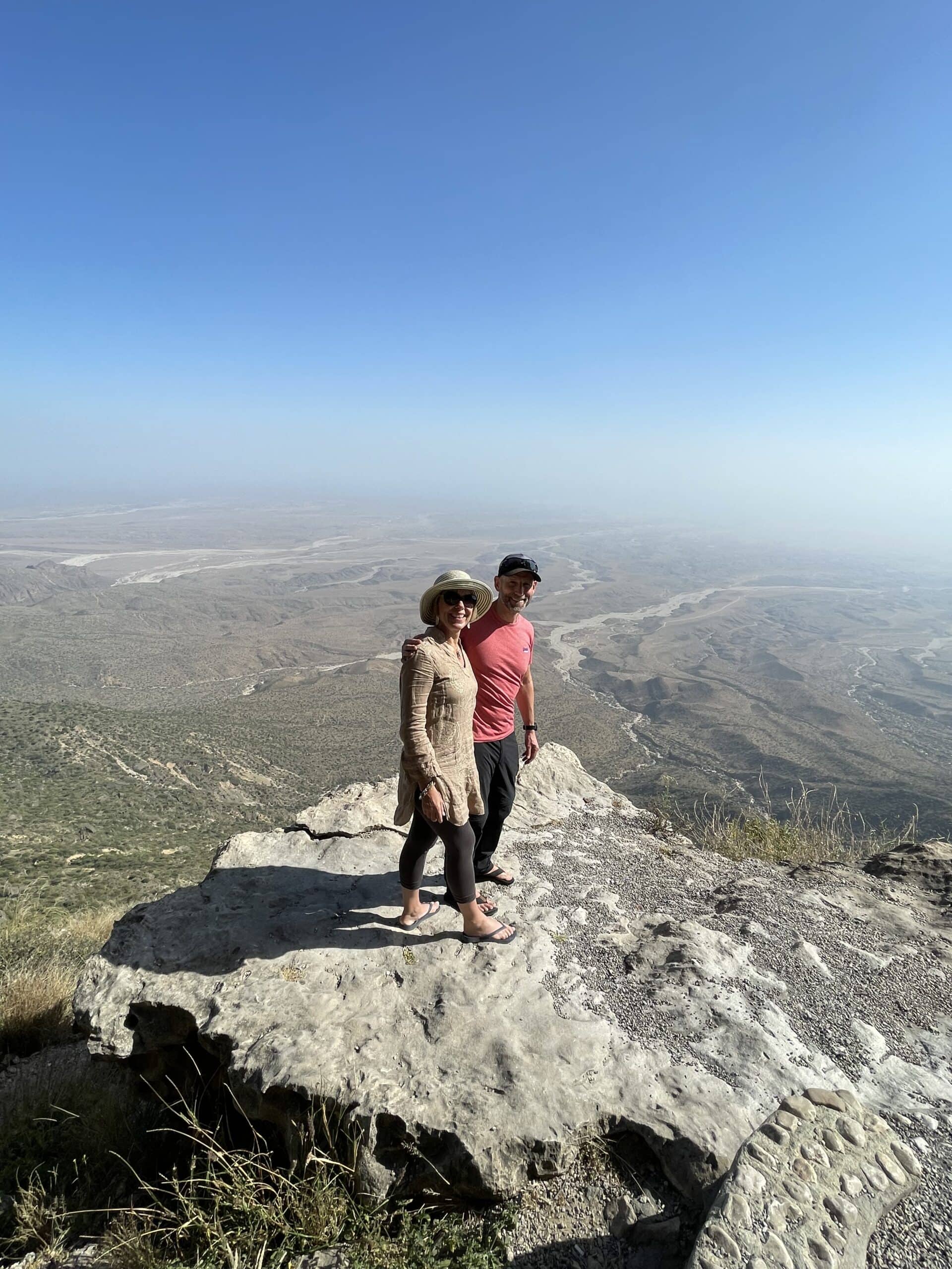 View from 1700m above sealevel Travellers on a rock at 1700m above sea level in Oman with blue sky in the background