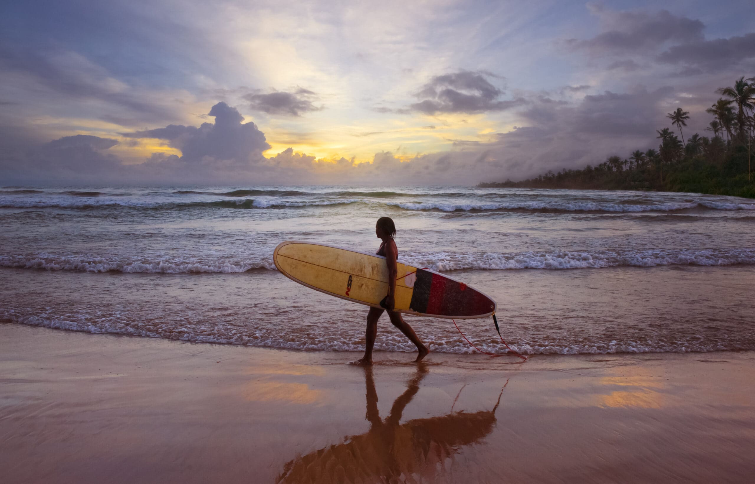 Unawatuna, Sri Lanka, Girl on the beach holding her surfboard Unawatuna, Sri Lanka, Girl on the beach holding her surfboard
