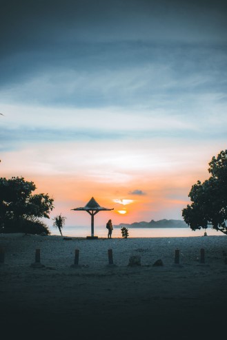 A person standing on Batu Bengkung Beach at sunset A person standing on Batu Bengkung Beach at sunset