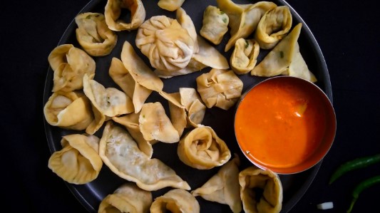 A plate of Momos (steamed buns) served with an orange chutney A plate of Momos (steamed buns) served with an orange chutney