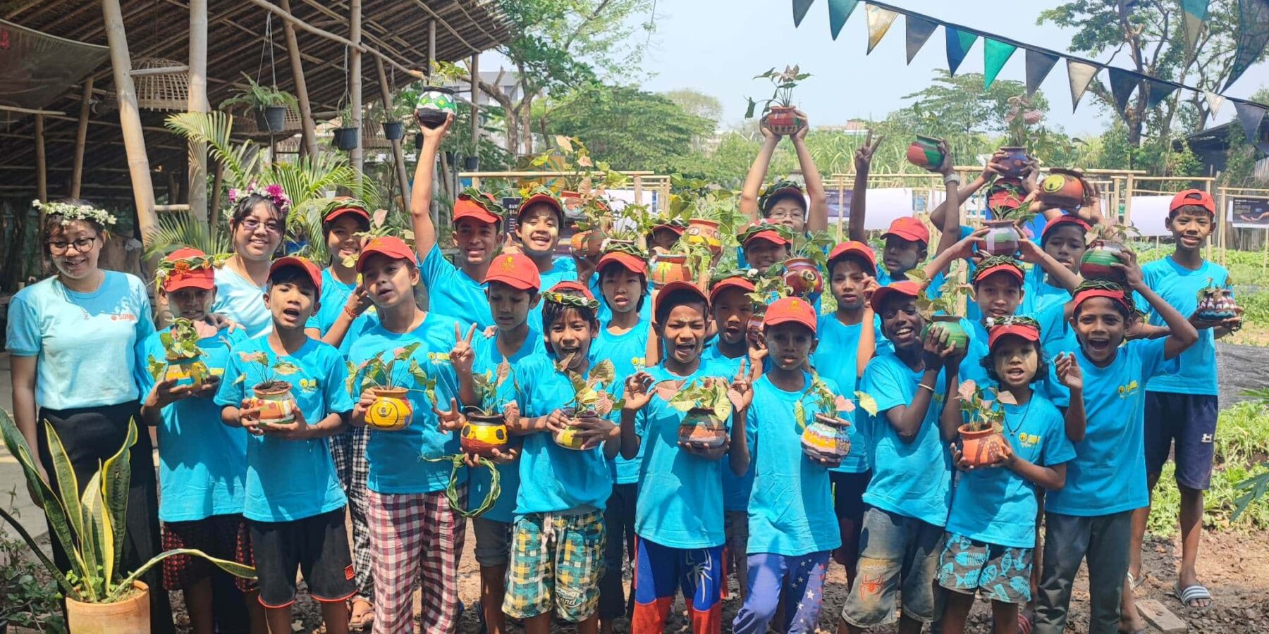 Myanmar trip A beaming group of children holding their farming projects at Kokkoya Organics Urban Farm in Yangon, Myanmar