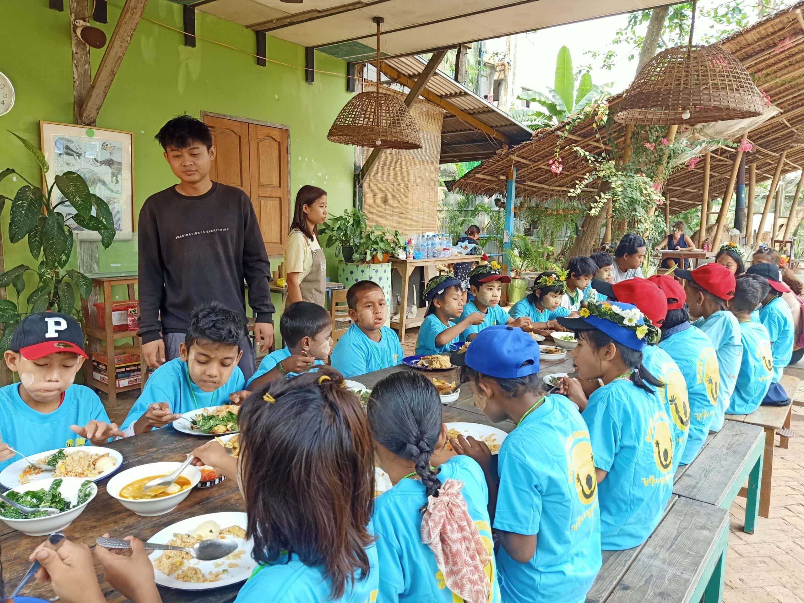 Myanmar trip (4) Happy children gather round a table eating an organic meal at Kokkoya Organic Farm, Yangon, Myanmar
